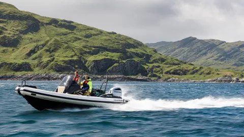 Twee mannen op een boot met Honda motoren op een meer. 