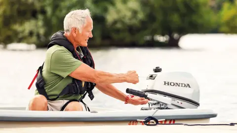 Man op een boot die een Honda BF5 motor start.