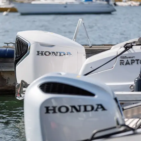 Close-up van Honda-motoren op de achterkant van boten op het water. 