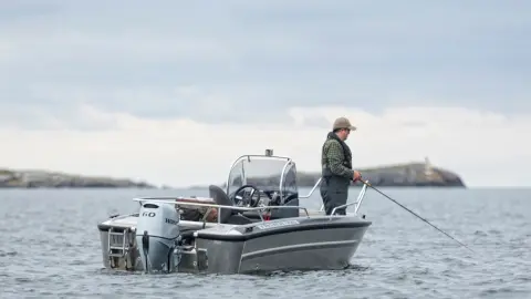 Een man aan het vissen op een boot met Honda BF60 motor.